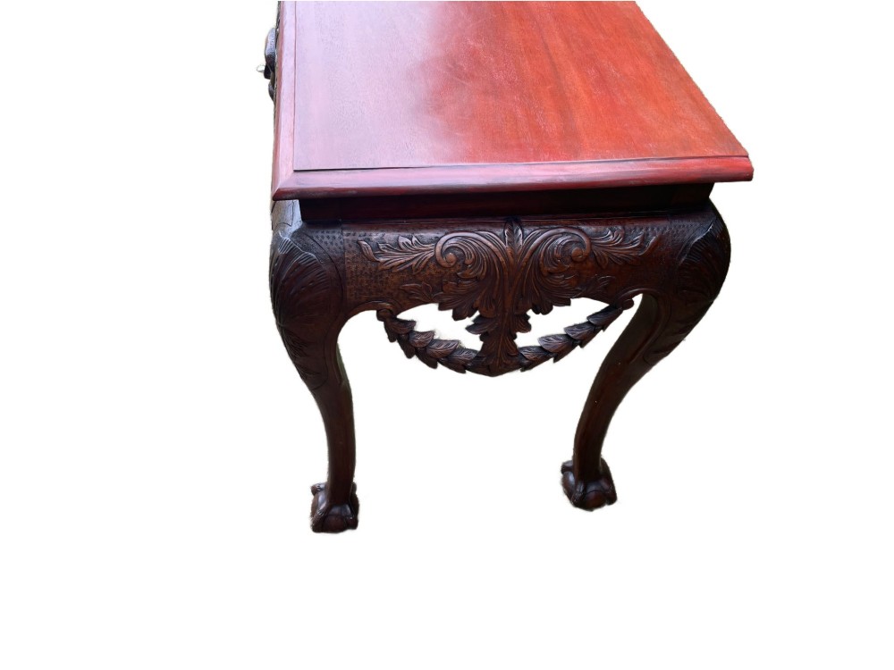 An Edwardian George II style mahogany serving table with an intricately carved apron featuring a central mask motif, raised on cabriole legs with claw and ball feet. View IX