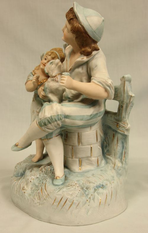 fig 1. A Victorian bisque porcelain figurine group depicting two children and a small dog with pale blue glazes and gilt accents.
