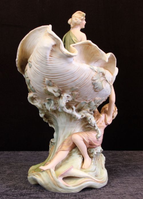 fig 1. An Art Nouveau Royal Dux porcelain centrepiece featuring a large shell-shaped bowl with two sculpted female figures and floral accents in cream, pink, and green tones.
