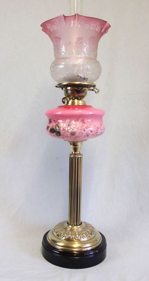 fig 1. An antique Victorian oil lamp featuring an etched frilled cranberry glass shade, hand-painted floral pink glass reservoir, brass reeded column, and clear glass chimney.