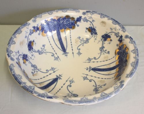fig 1. A large round antique ceramic wash bowl decorated with blue floral transferware patterns and gold gilt detailing on a white glaze.
