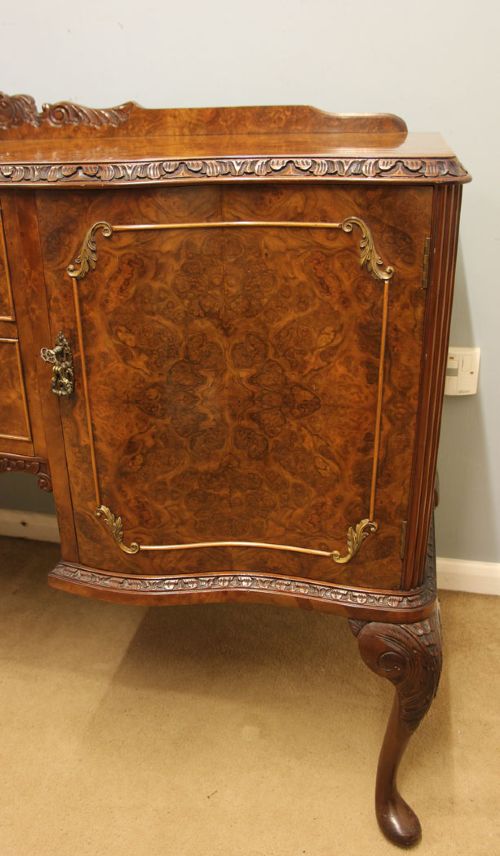 A burr walnut serpentine front sideboard featuring two central drawers flanked by side cupboards and raised on carved cabriole legs. View III