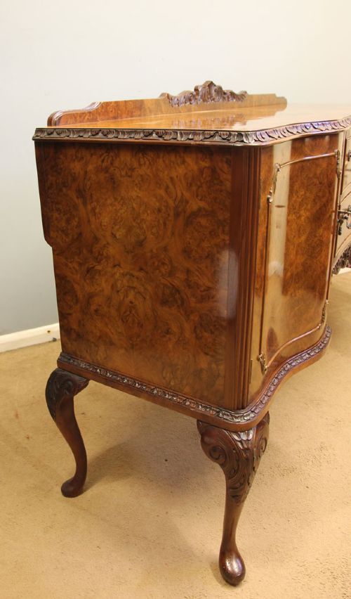 A burr walnut serpentine front sideboard featuring two central drawers flanked by side cupboards and raised on carved cabriole legs. View V