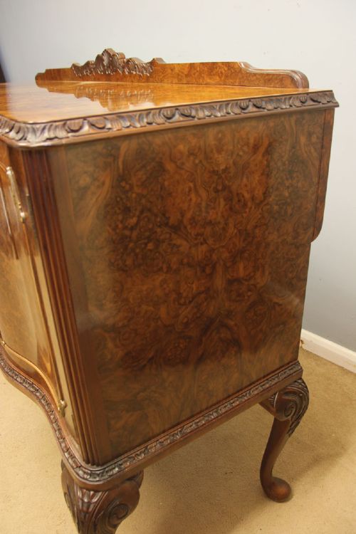 A burr walnut serpentine front sideboard featuring two central drawers flanked by side cupboards and raised on carved cabriole legs. View IX