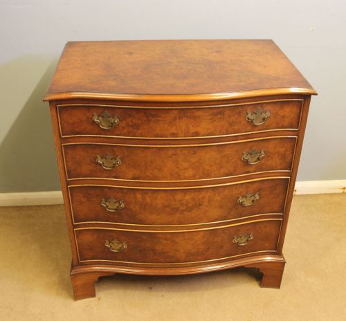 fig 1. A burr walnut chest of drawers featuring four graduated drawers with a serpentine curved front, decorative brass handles, and resting on bracket feet.