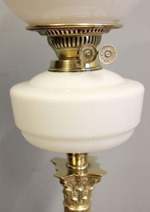An antique oil lamp featuring a stepped brass Corinthian column base, a white glass font, a clear glass chimney, and a spherical white glass shade painted with a winter landscape. View IX