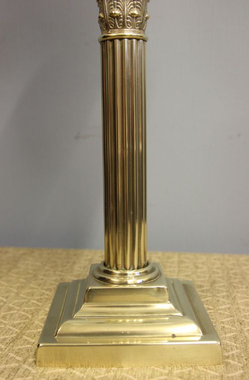 An antique oil lamp featuring a stepped brass Corinthian column base, a white glass font, a clear glass chimney, and a spherical white glass shade painted with a winter landscape. View XI