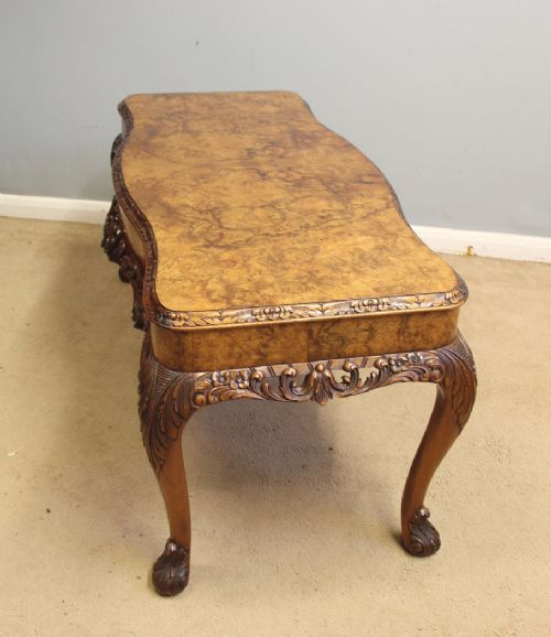 fig 1. A low Queen Anne style burr walnut coffee table featuring carved cabriole legs, an ornate apron, and a serpentine book-matched top.