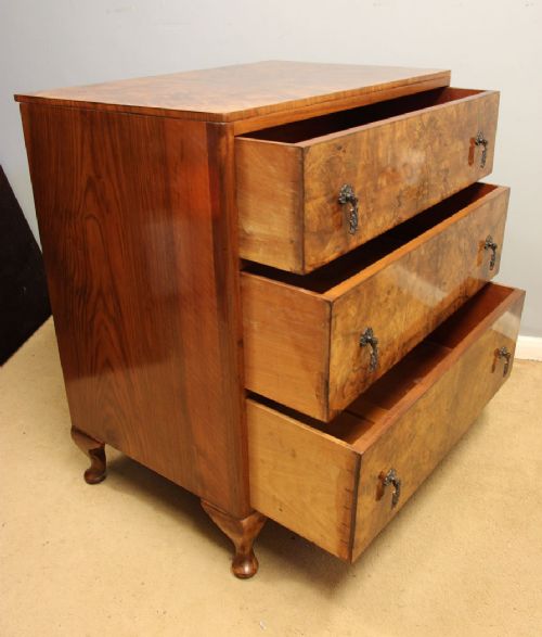 A three-drawer burr walnut chest of drawers featuring book-matched veneer patterns, ornate brass drop handles, and short cabriole legs. View VIII