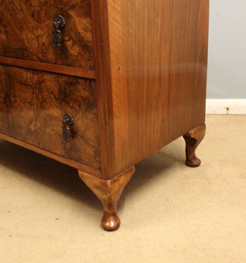 A three-drawer burr walnut chest of drawers featuring book-matched veneer patterns, ornate brass drop handles, and short cabriole legs. View IX
