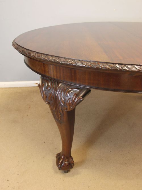 An oval mahogany extending dining table with two insert leaves, carved border edging, cabriole legs featuring acanthus knee carvings, and ball-and-claw feet. View VI
