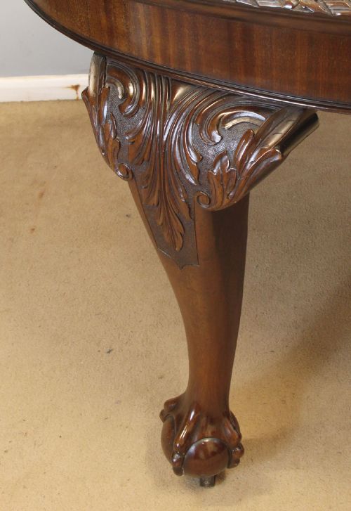 An oval mahogany extending dining table with two insert leaves, carved border edging, cabriole legs featuring acanthus knee carvings, and ball-and-claw feet. View X