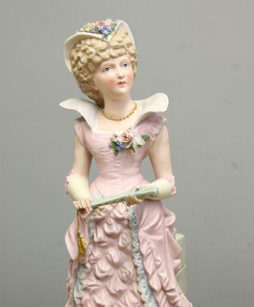 fig 1. A pair of antique matte bisque porcelain figurines depicting a lady and gentleman dressed in pastel pink eighteenth-century period costume.