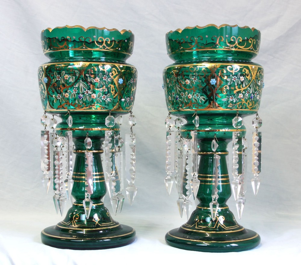 A pair of Victorian emerald green glass mantle lustres featuring hand-painted floral gilt decoration and clear faceted cut crystal prisms.