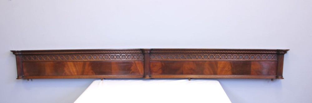 A long antique flame mahogany architectural pediment featuring a geometric carved frieze and fluted end pilasters.