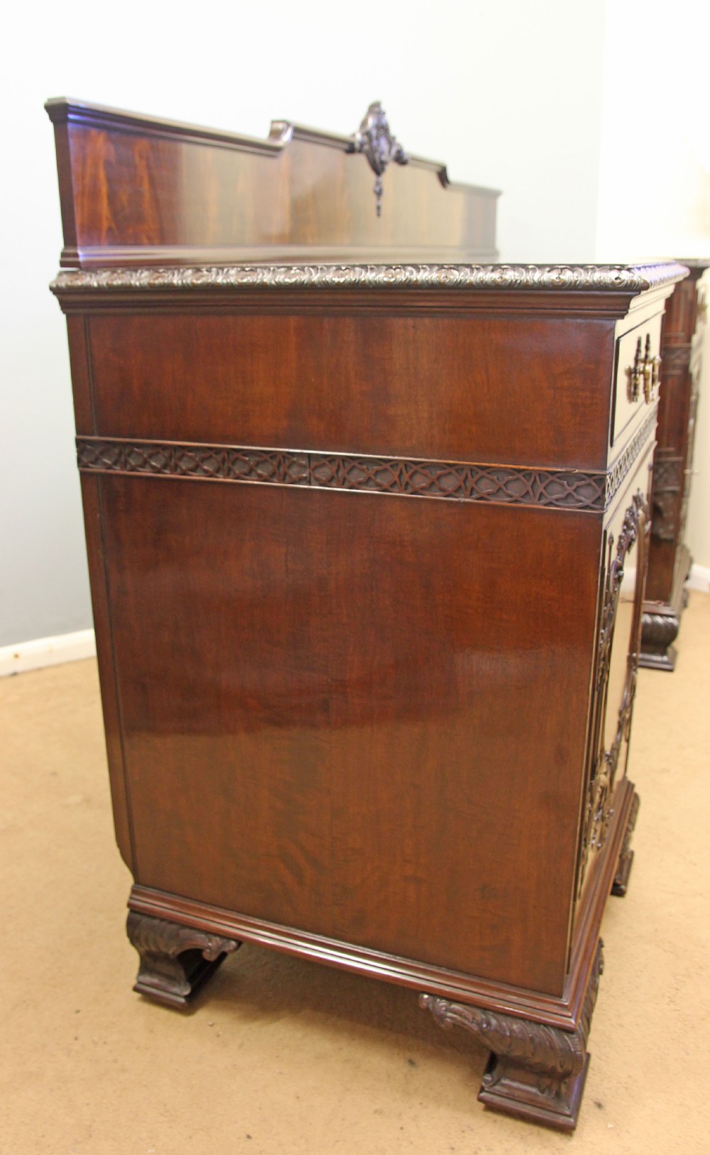 An antique dark mahogany sideboard featuring carved panels, brass swan-neck handles, double cupboard doors, and claw-and-ball feet. View XIII