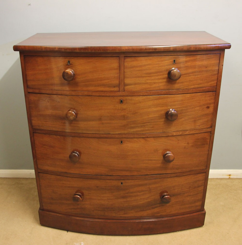 A Victorian mahogany bow front chest of drawers featuring a two over three drawer layout with turned wooden handles and a curved plinth base.