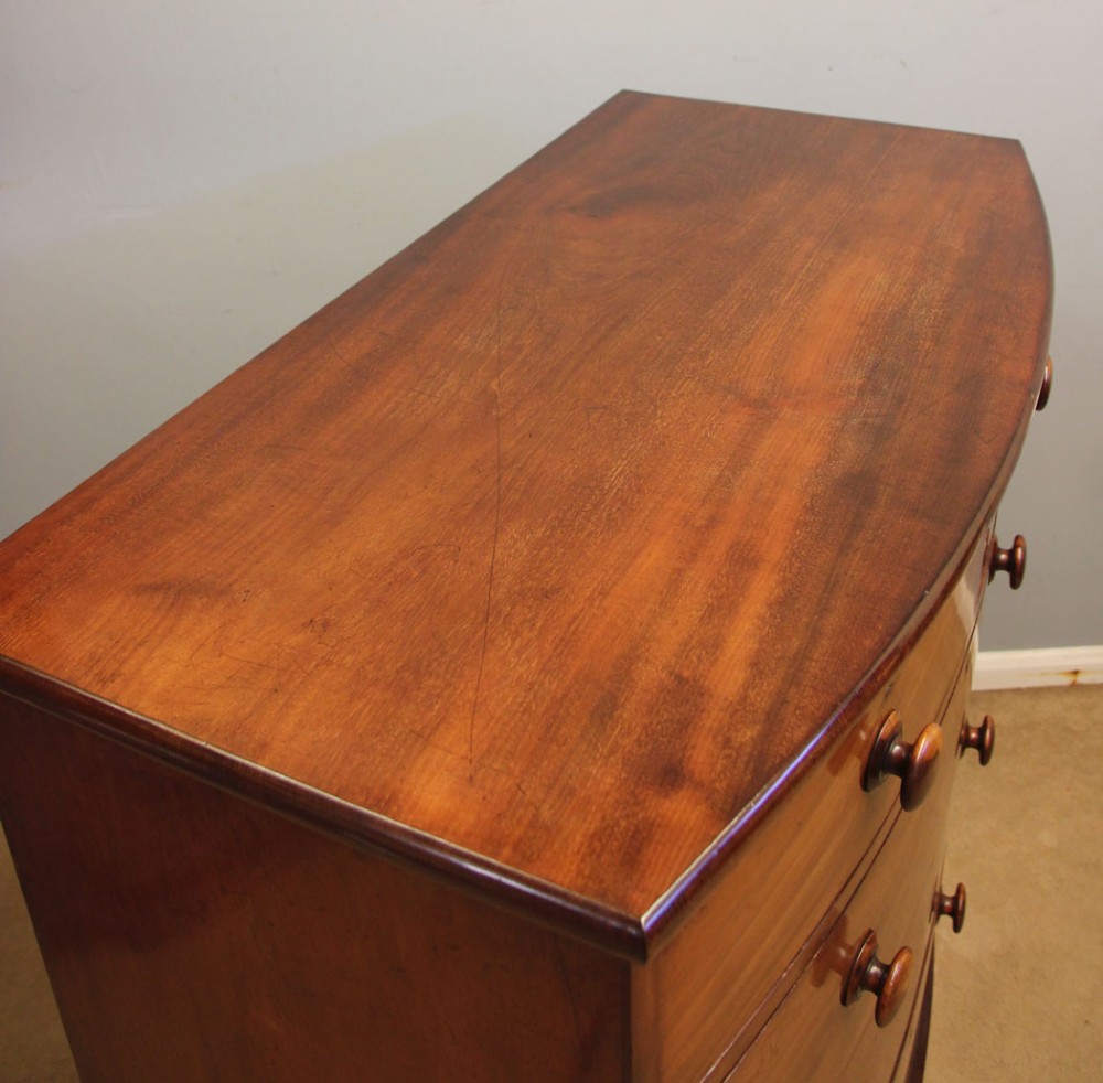 A Victorian mahogany bow front chest of drawers featuring a two over three drawer layout with turned wooden handles and a curved plinth base. View IV