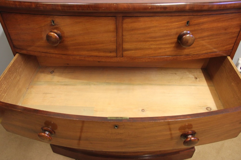 A Victorian mahogany bow front chest of drawers featuring a two over three drawer layout with turned wooden handles and a curved plinth base. View VI