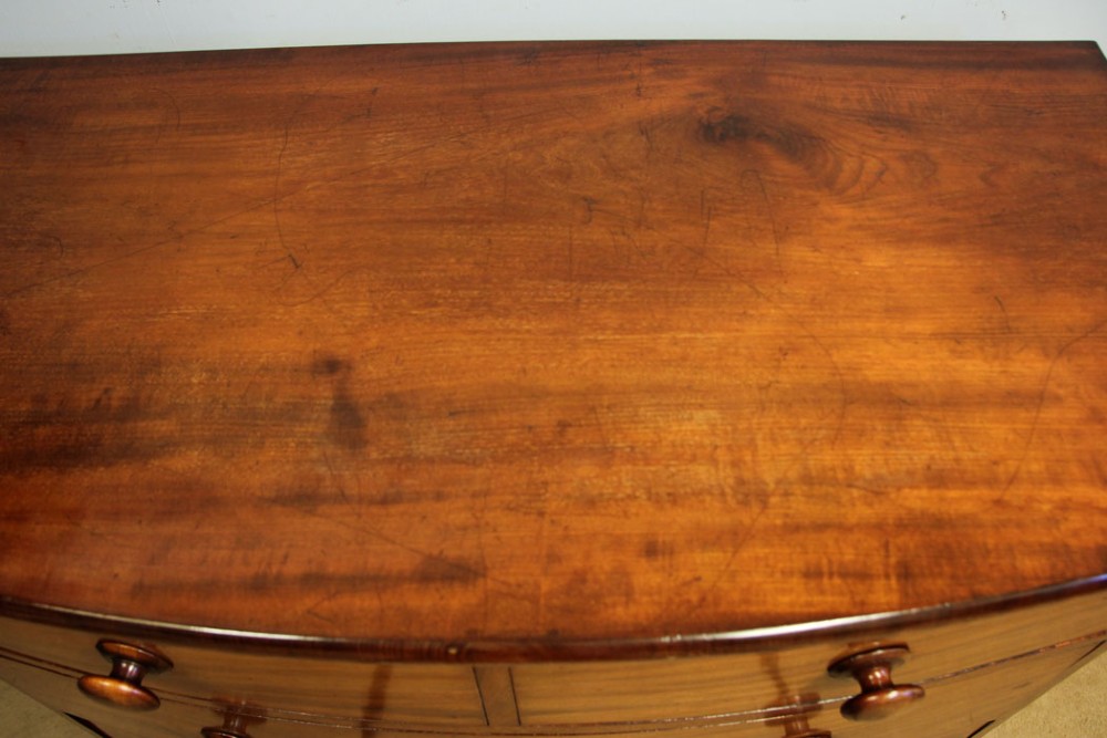 A Victorian mahogany bow front chest of drawers featuring a two over three drawer layout with turned wooden handles and a curved plinth base. View XII