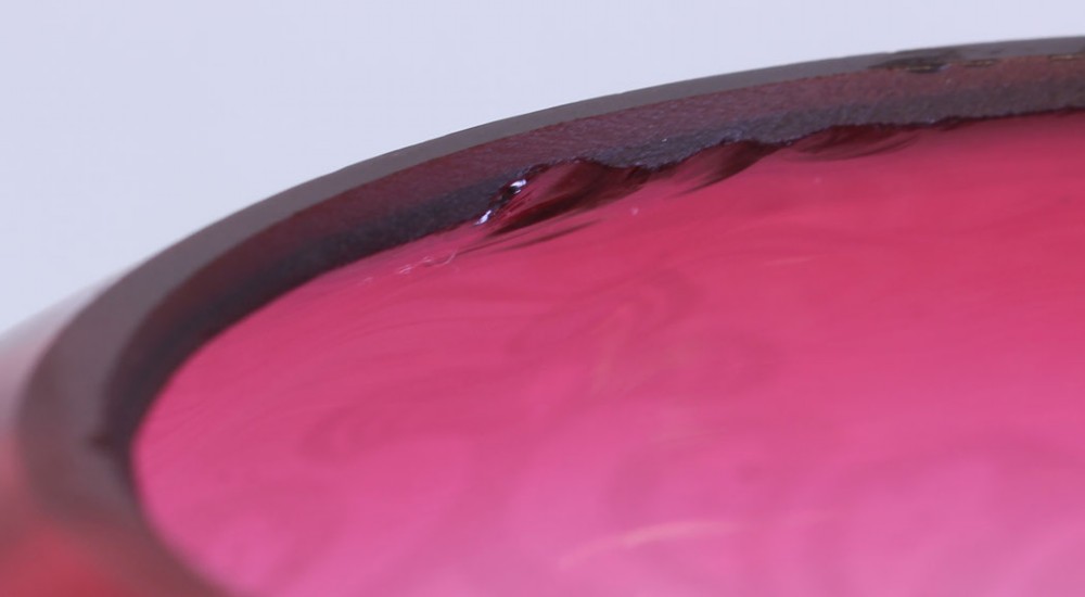 A dome-shaped Victorian cranberry glass oil lamp shade with acid-etched floral and foliate scrolling motifs fading from deep pink to clear glass. View VII