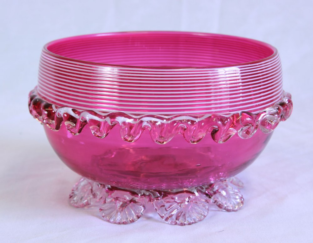 A Victorian cranberry pink glass bowl featuring fine horizontal white threading, an applied clear frilled band, and shell-shaped clear glass feet. View II