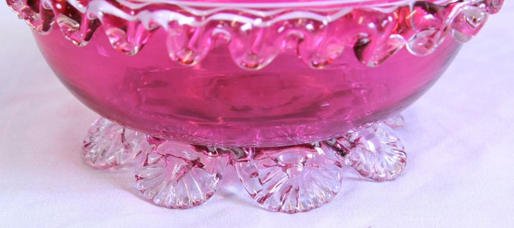 A Victorian cranberry pink glass bowl featuring fine horizontal white threading, an applied clear frilled band, and shell-shaped clear glass feet. View V