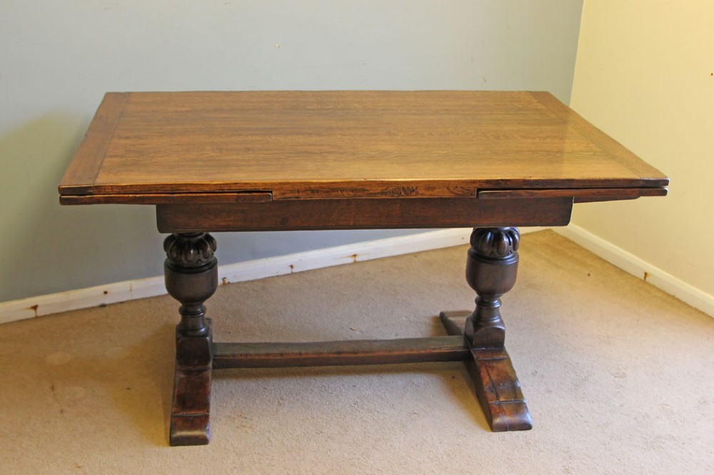 A solid oak extending refectory dining table featuring carved bulbous legs and an H-stretcher base.