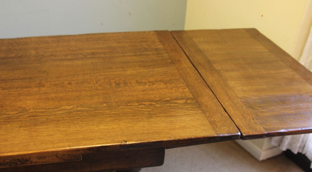 A solid oak extending refectory dining table featuring carved bulbous legs and an H-stretcher base. View VIII