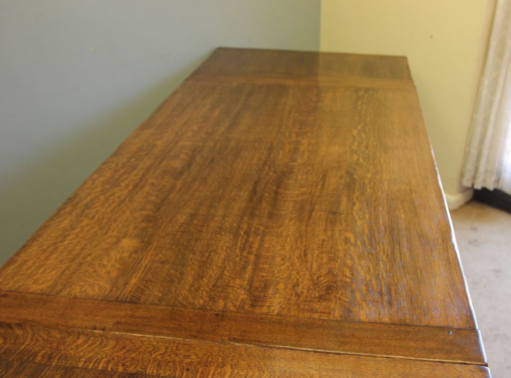 A solid oak extending refectory dining table featuring carved bulbous legs and an H-stretcher base. View IX