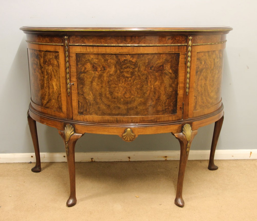A semi-circular burr walnut side cabinet featuring cabriole legs with shell carvings and brass mounts. View III