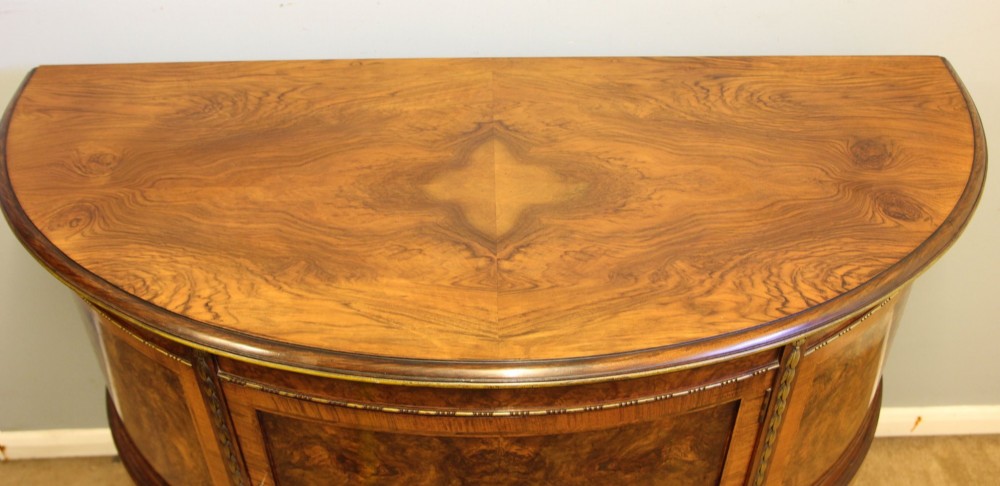 A semi-circular burr walnut side cabinet featuring cabriole legs with shell carvings and brass mounts. View IV