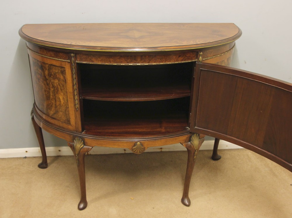 A semi-circular burr walnut side cabinet featuring cabriole legs with shell carvings and brass mounts. View VI