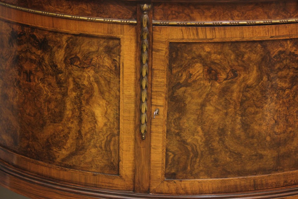 A semi-circular burr walnut side cabinet featuring cabriole legs with shell carvings and brass mounts. View VII