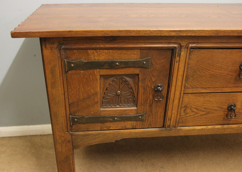 An antique oak sideboard with two central drawers, two carved panel doors with iron strap hinges, and sturdy square legs. View VI