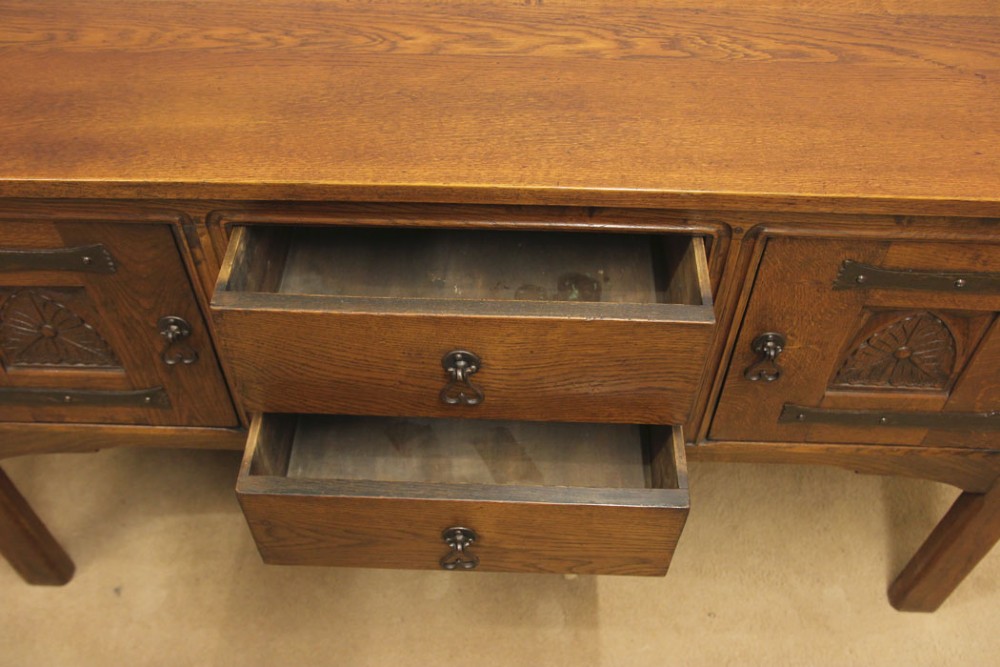 An antique oak sideboard with two central drawers, two carved panel doors with iron strap hinges, and sturdy square legs. View VIII