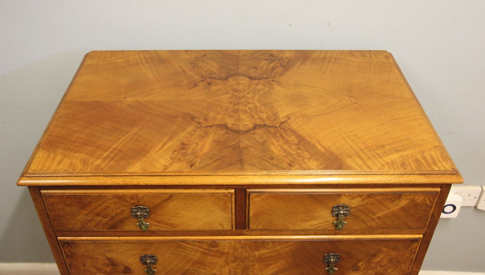 An antique figured walnut chest featuring two short drawers over three long drawers, resting on elevated cabriole legs with brass drop handles. View III