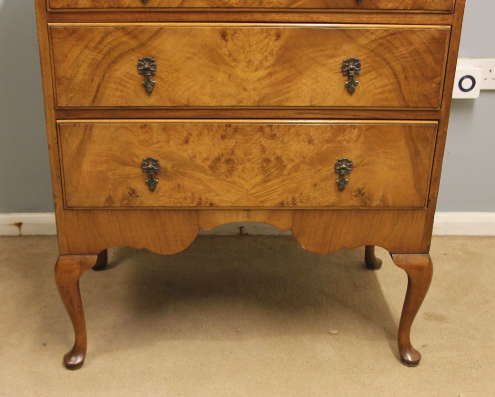 An antique figured walnut chest featuring two short drawers over three long drawers, resting on elevated cabriole legs with brass drop handles. View VI