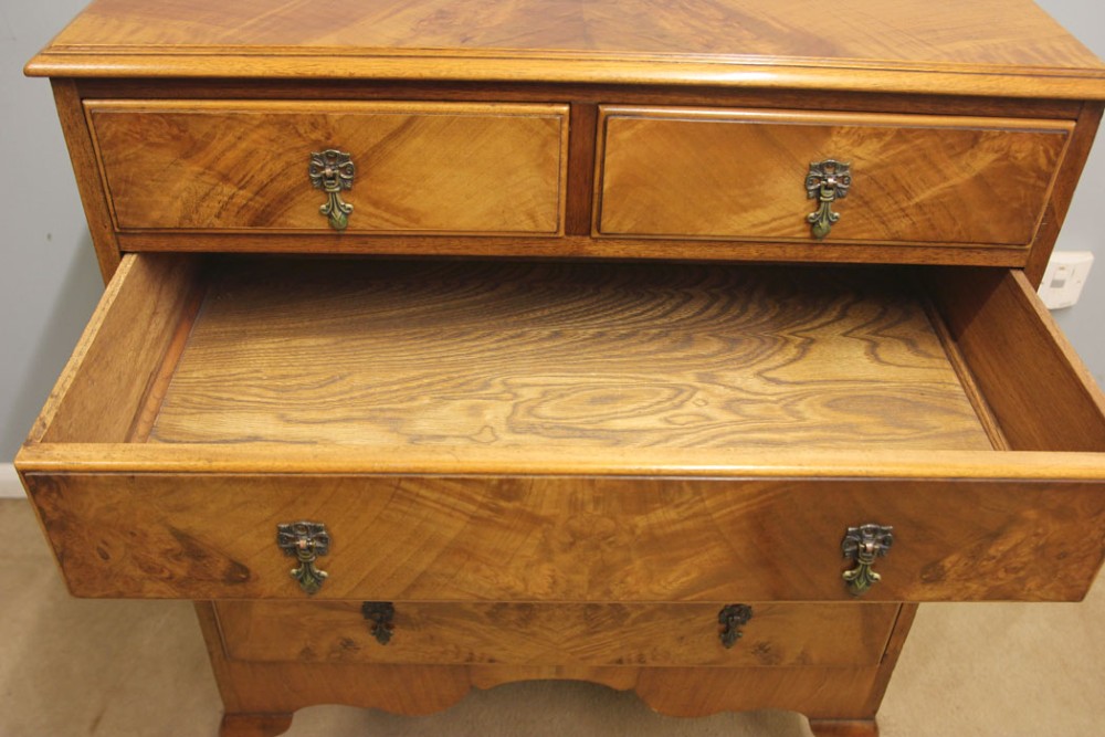 An antique figured walnut chest featuring two short drawers over three long drawers, resting on elevated cabriole legs with brass drop handles. View VIII