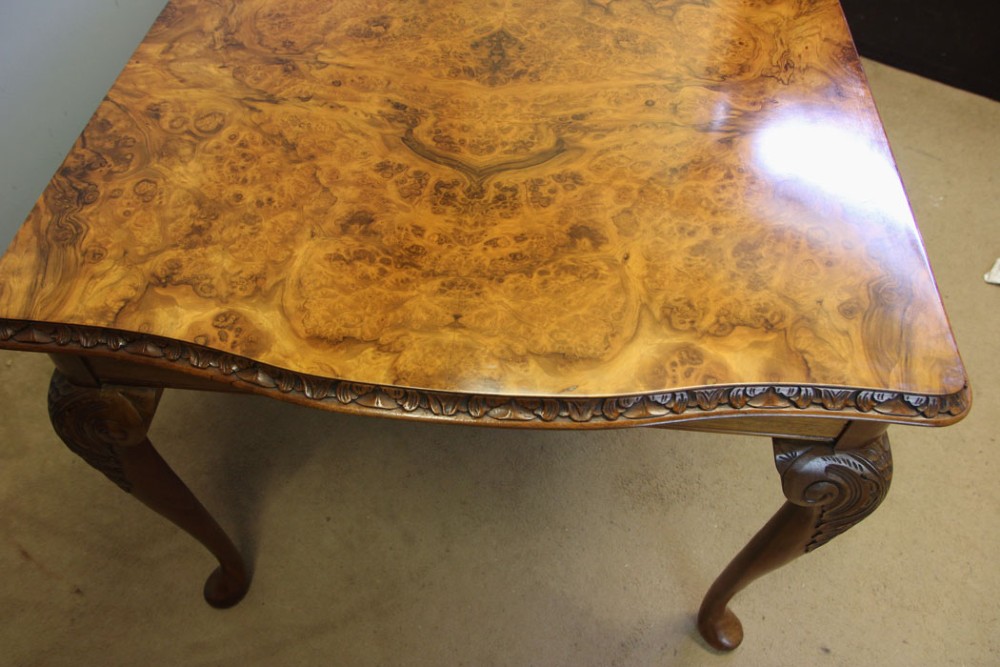 A rectangular burr walnut dining table featuring symmetrical book-matched veneer across the top, carved edge moulding, and cabriole legs. View III