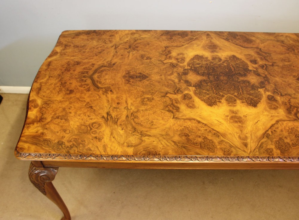 A rectangular burr walnut dining table featuring symmetrical book-matched veneer across the top, carved edge moulding, and cabriole legs. View V