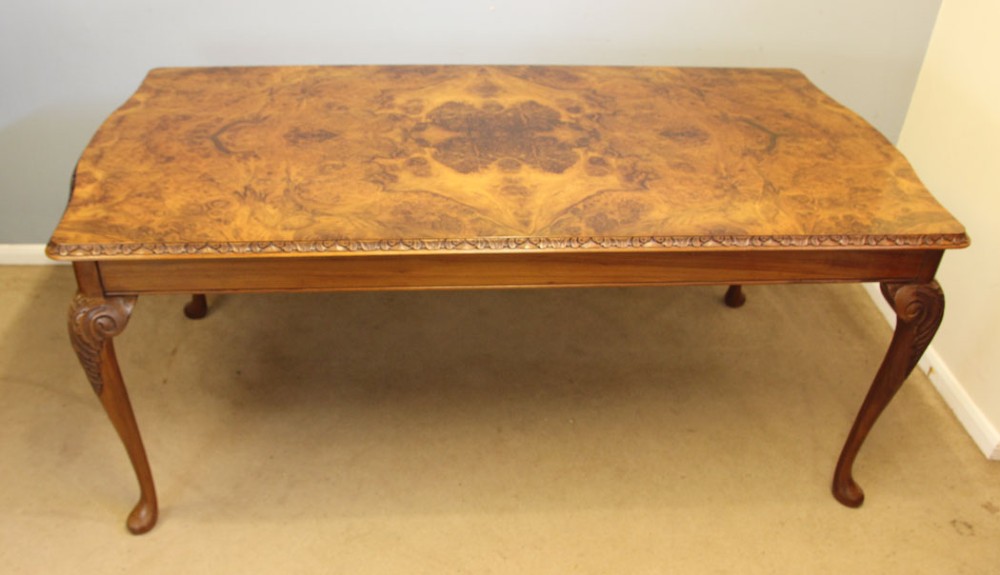 A rectangular burr walnut dining table featuring symmetrical book-matched veneer across the top, carved edge moulding, and cabriole legs. View VI