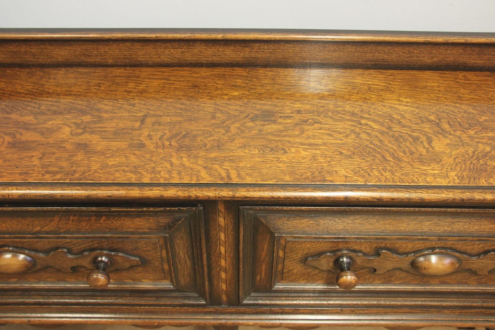 An antique dark oak side table with two geometric-panelled drawers, turned legs, a low stretcher base, and a raised backboard. View V