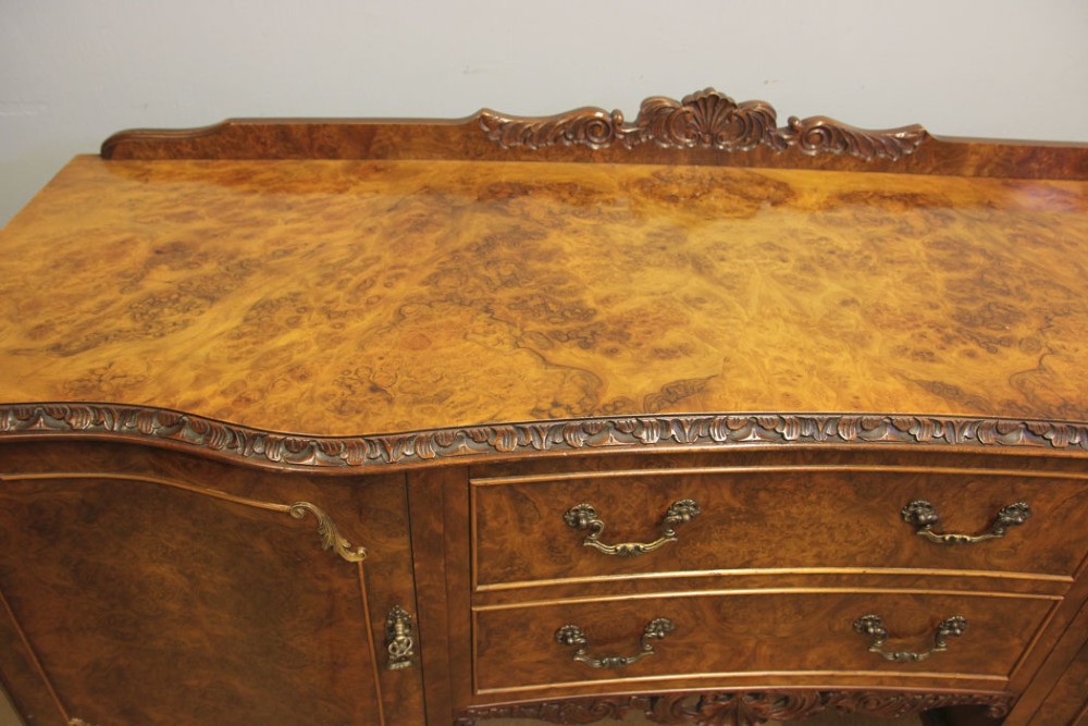 A burr walnut serpentine front sideboard featuring two central drawers flanked by side cupboards and raised on carved cabriole legs. View IV