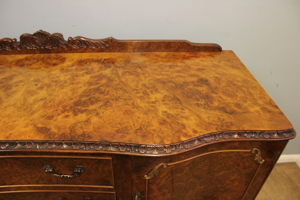 A burr walnut serpentine front sideboard featuring two central drawers flanked by side cupboards and raised on carved cabriole legs. View VI