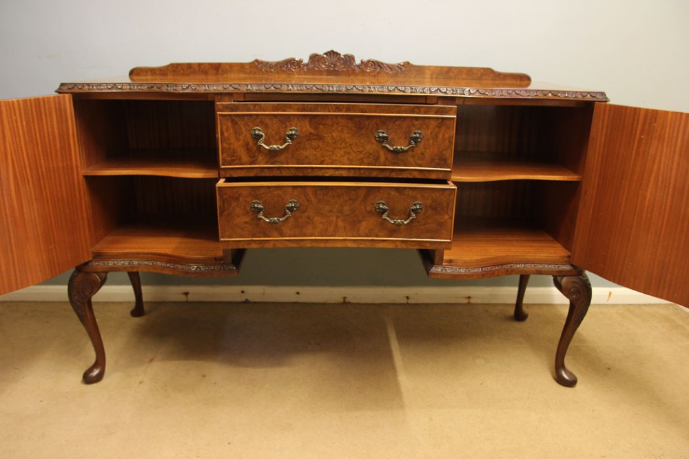 A burr walnut serpentine front sideboard featuring two central drawers flanked by side cupboards and raised on carved cabriole legs. View X