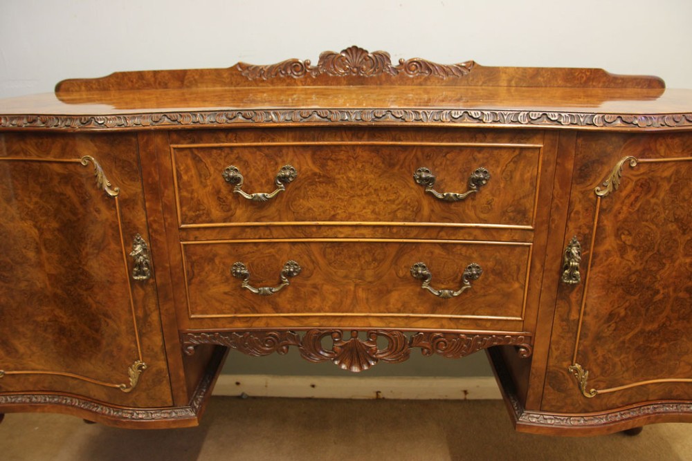 A burr walnut serpentine front sideboard featuring two central drawers flanked by side cupboards and raised on carved cabriole legs. View XI