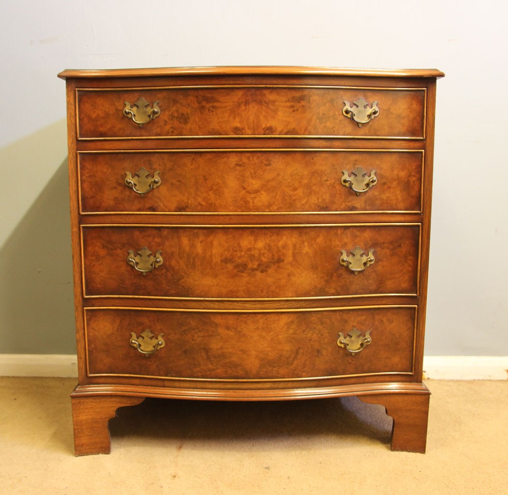 A burr walnut chest of drawers featuring four graduated drawers with a serpentine curved front, decorative brass handles, and resting on bracket feet.