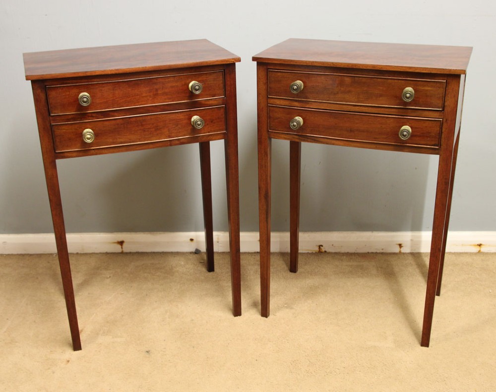 A pair of slim mahogany bedside tables, each featuring two drawers with brass knobs and tall square tapered legs.