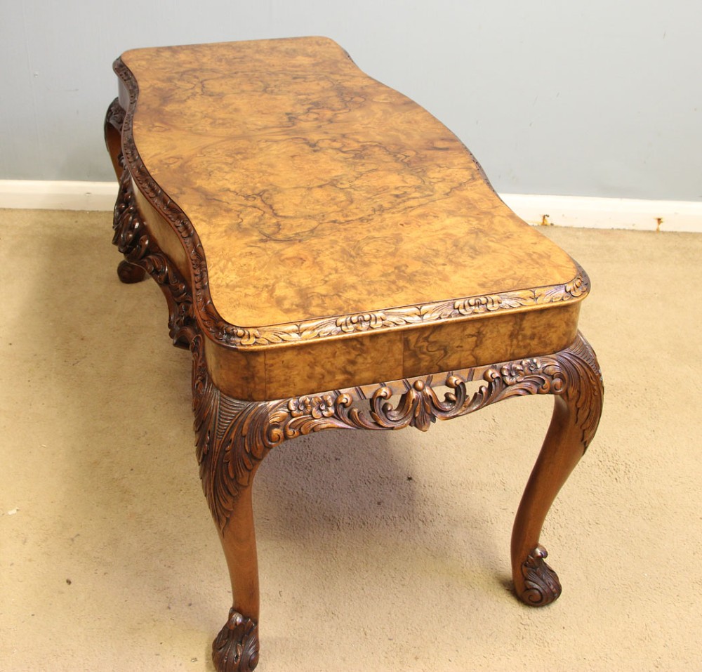 A low Queen Anne style burr walnut coffee table featuring carved cabriole legs, an ornate apron, and a serpentine book-matched top. View X